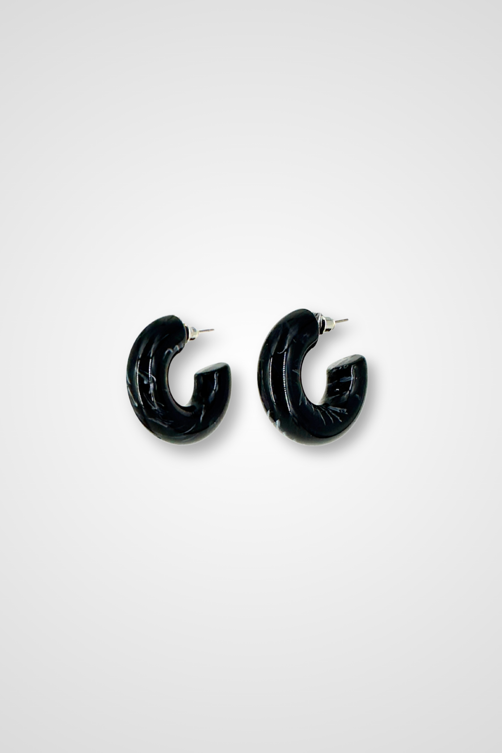 A pair of hoop earrings, mostly black but a little bit white in a marble pattern. Chunky design in plastic