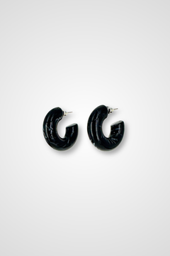 A pair of hoop earrings, mostly black but a little bit white in a marble pattern. Chunky design in plastic