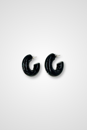 A pair of hoop earrings, mostly black but a little bit white in a marble pattern. Chunky design in plastic